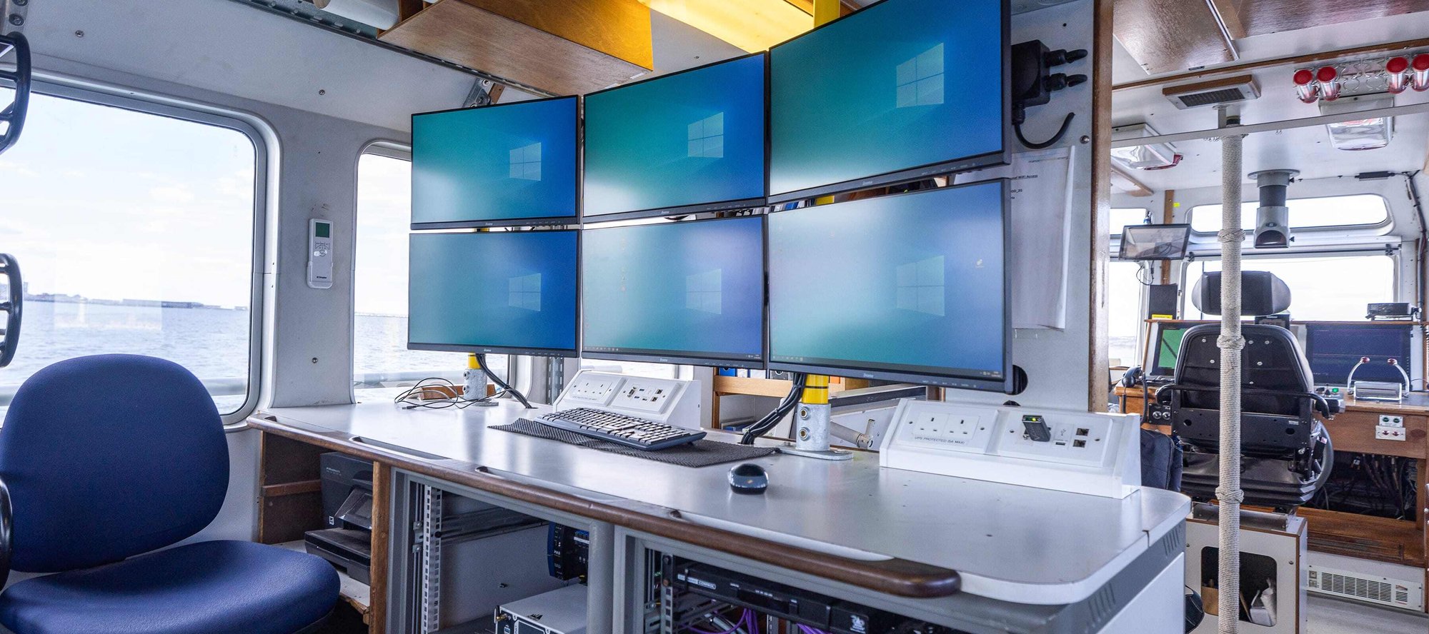 A view of inside the Manor Brunel survey vessel with six screens at a workstation.