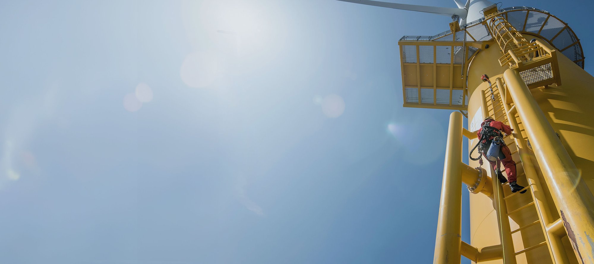 Man climbing ladder on side of wind turbine